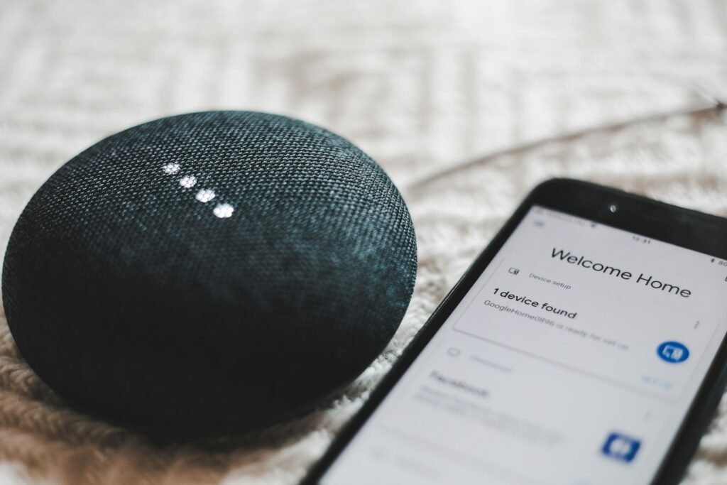 A Google Home Mini smart speaker next to a smartphone