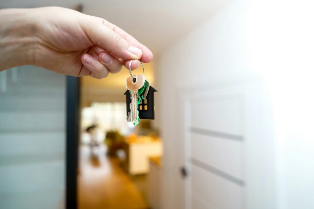A person holding house keys in front of a home entrance