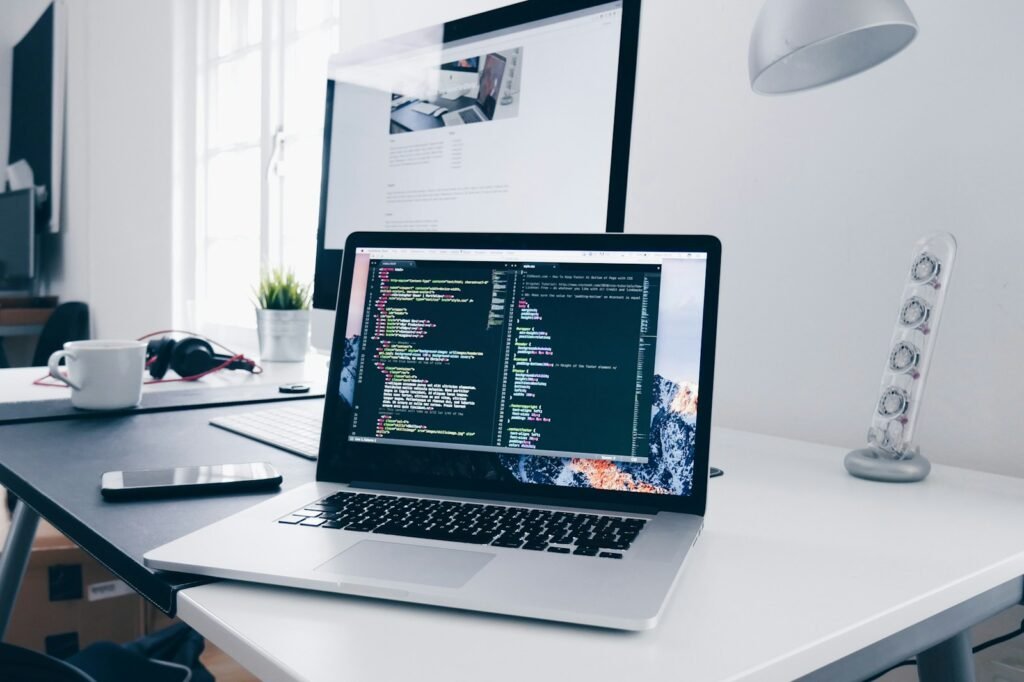 A laptop showing website code on a busy desk